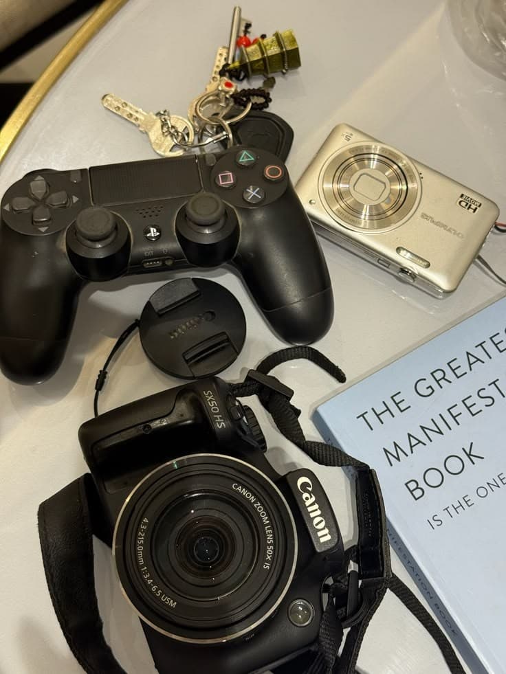 A camera, game controller, keys and a book on a table