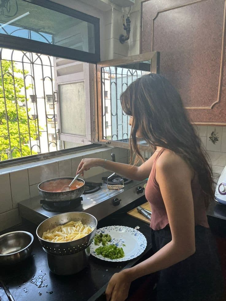 Someone cooking pasta by a kitchen window