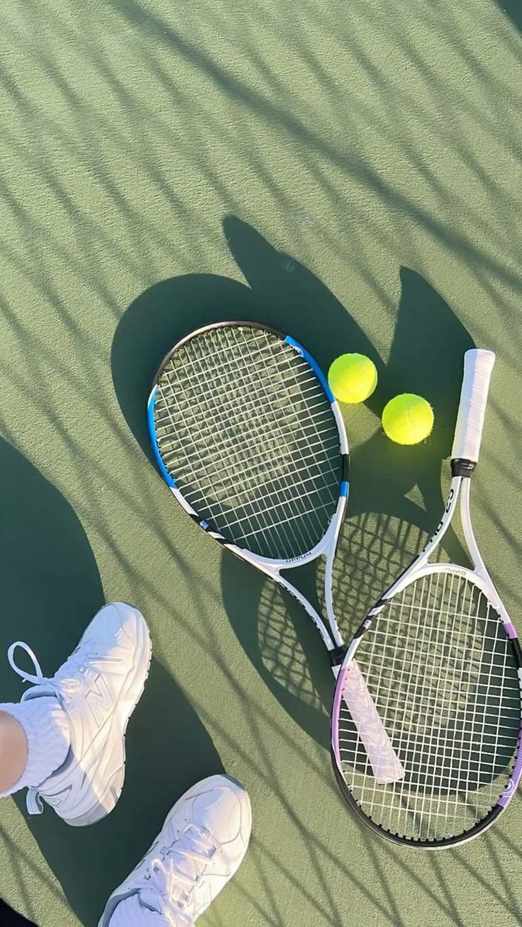 Two tennis rackets and balls on a court